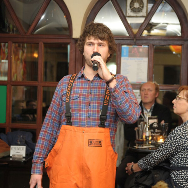 Ein Mann mit einer orangen Hose hält ein Mikrofon. 